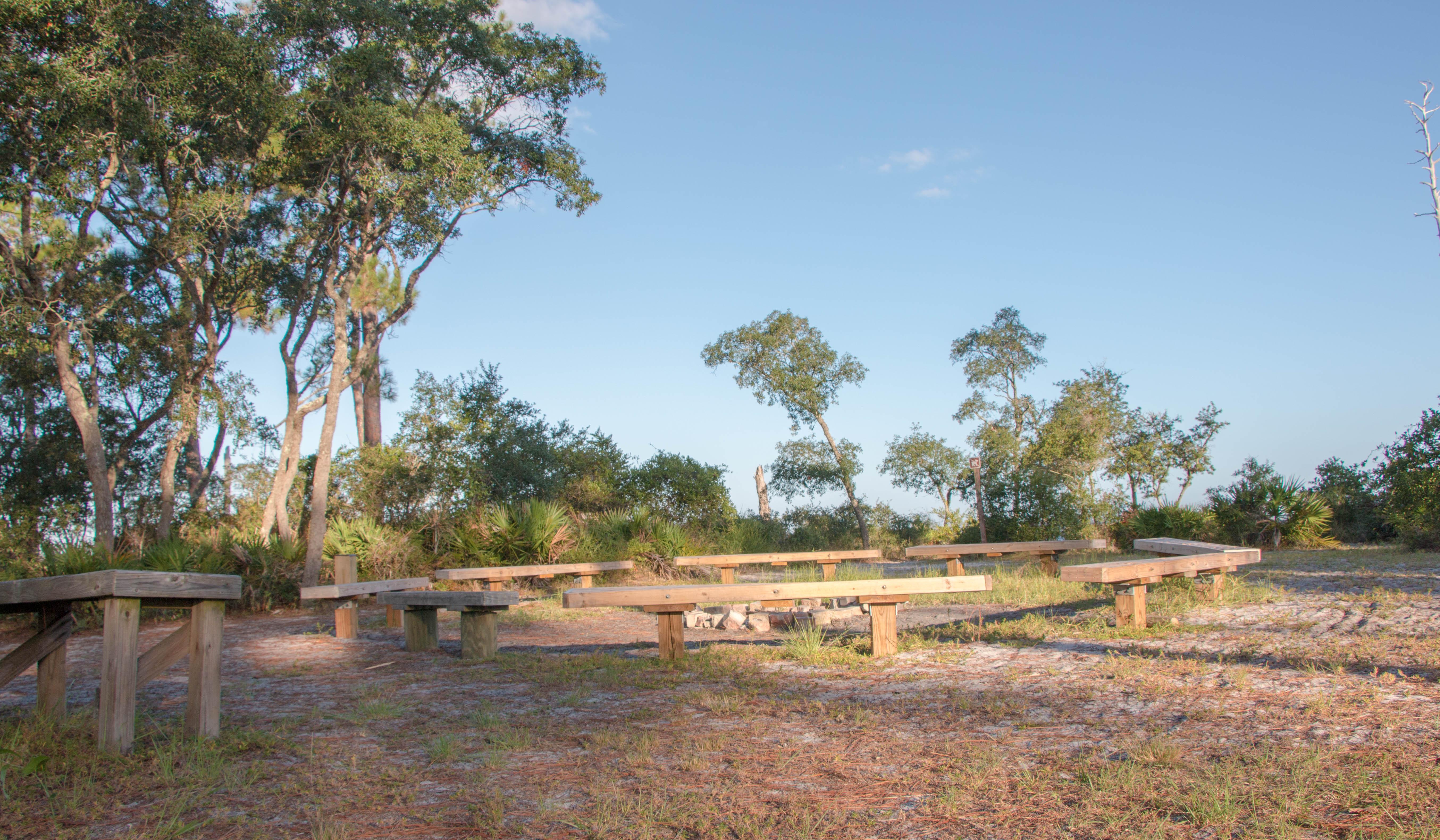 Wooden benches surround the campfire ring a the Naval Live Oaks Youth Campground.