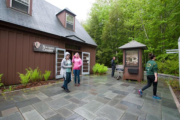 People standing outside a brown building with a stone patio around it