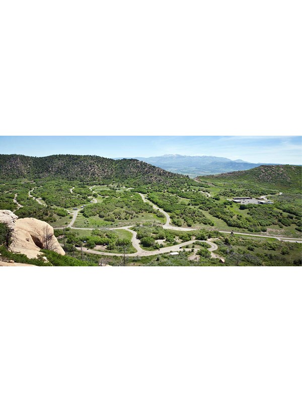 Expansive, overhead view of loop roads and campsites within a green valley surrounded by hills