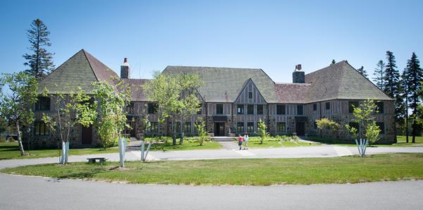 A large brick and slate building with blue detailing and a front walkway from a parking area