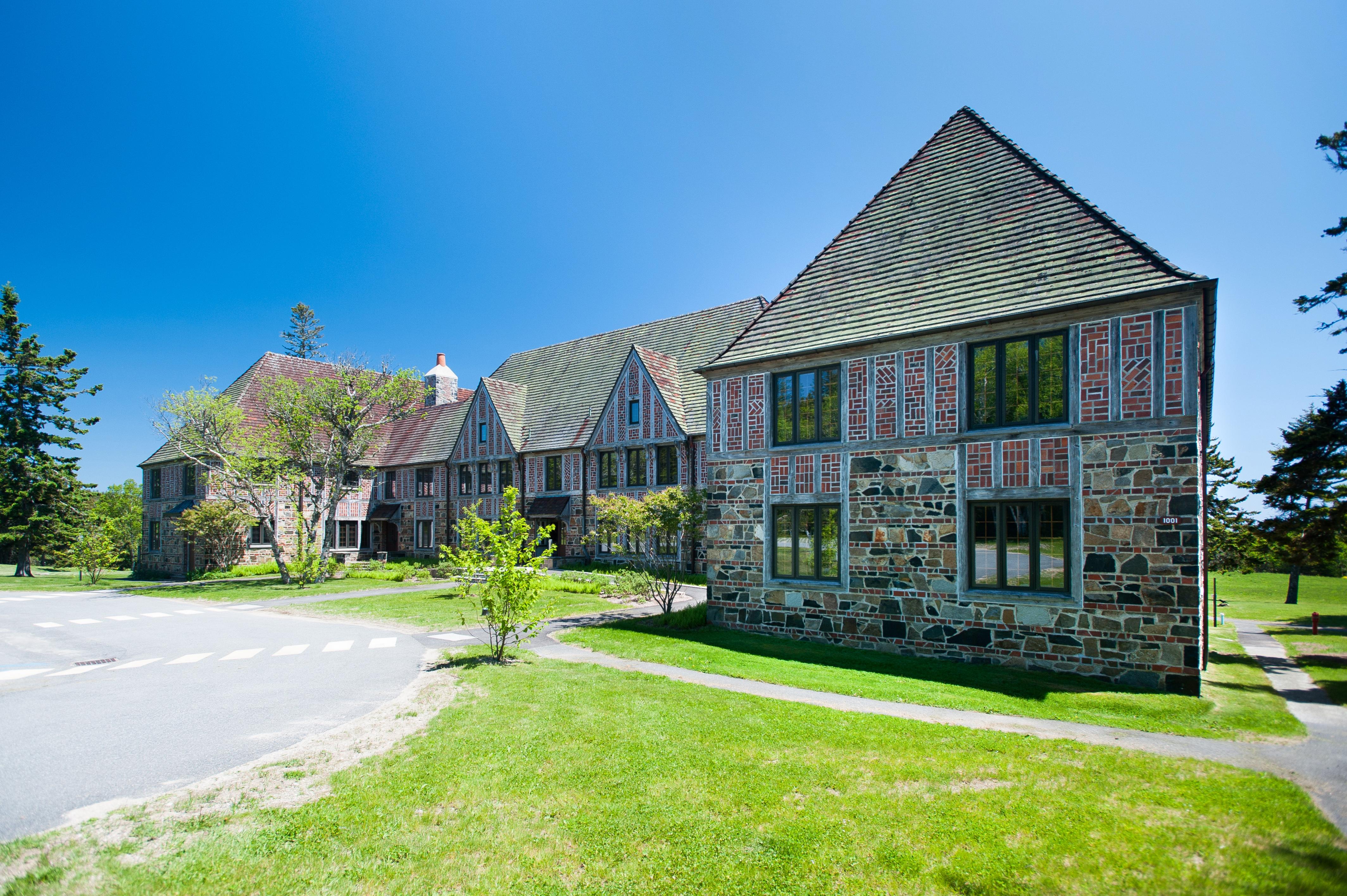 A large brick and slate building with blue detailing and a front walkway from a parking area