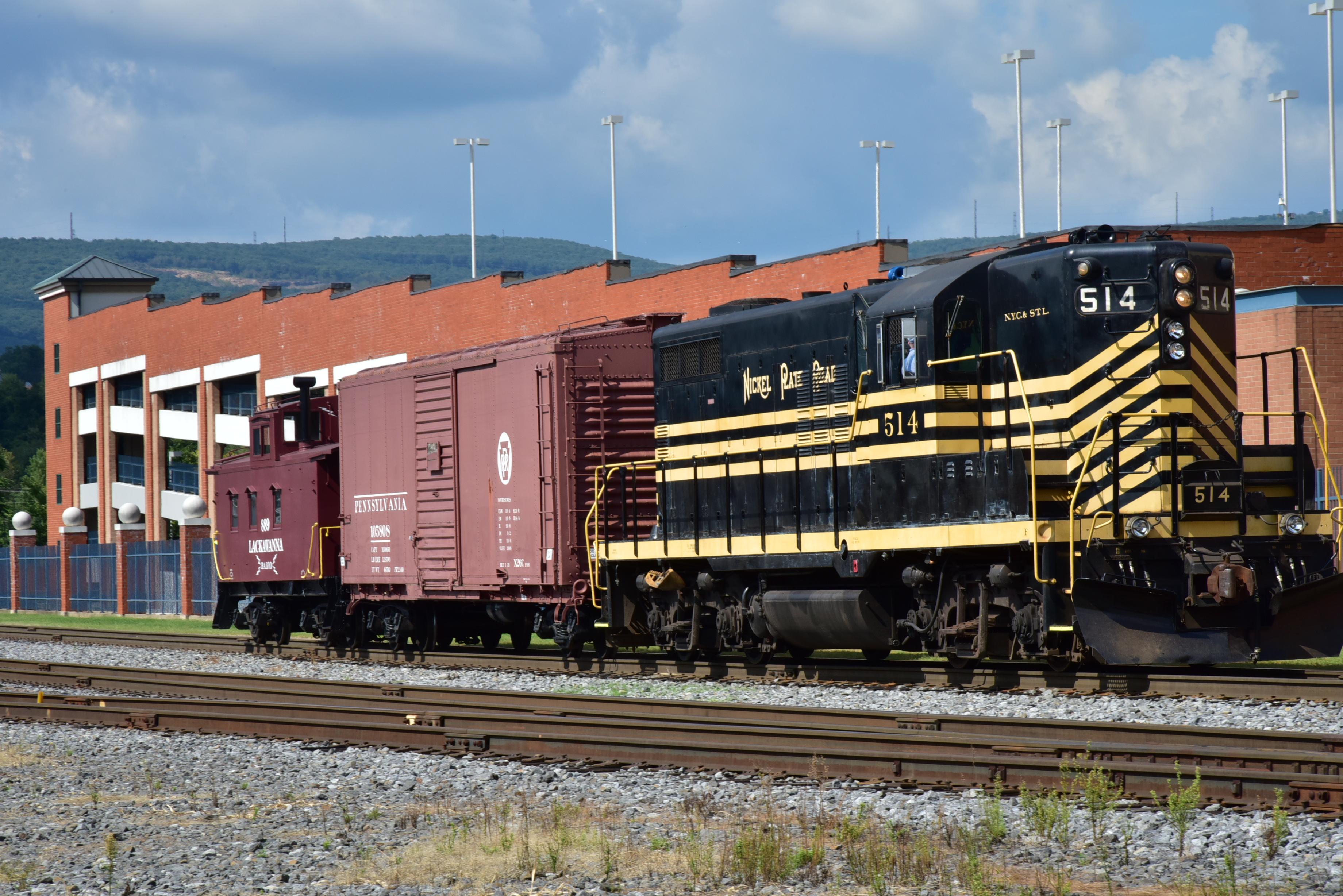 Black and yellow diesel engine 514 pulling a faded red box car and a dark red caboose