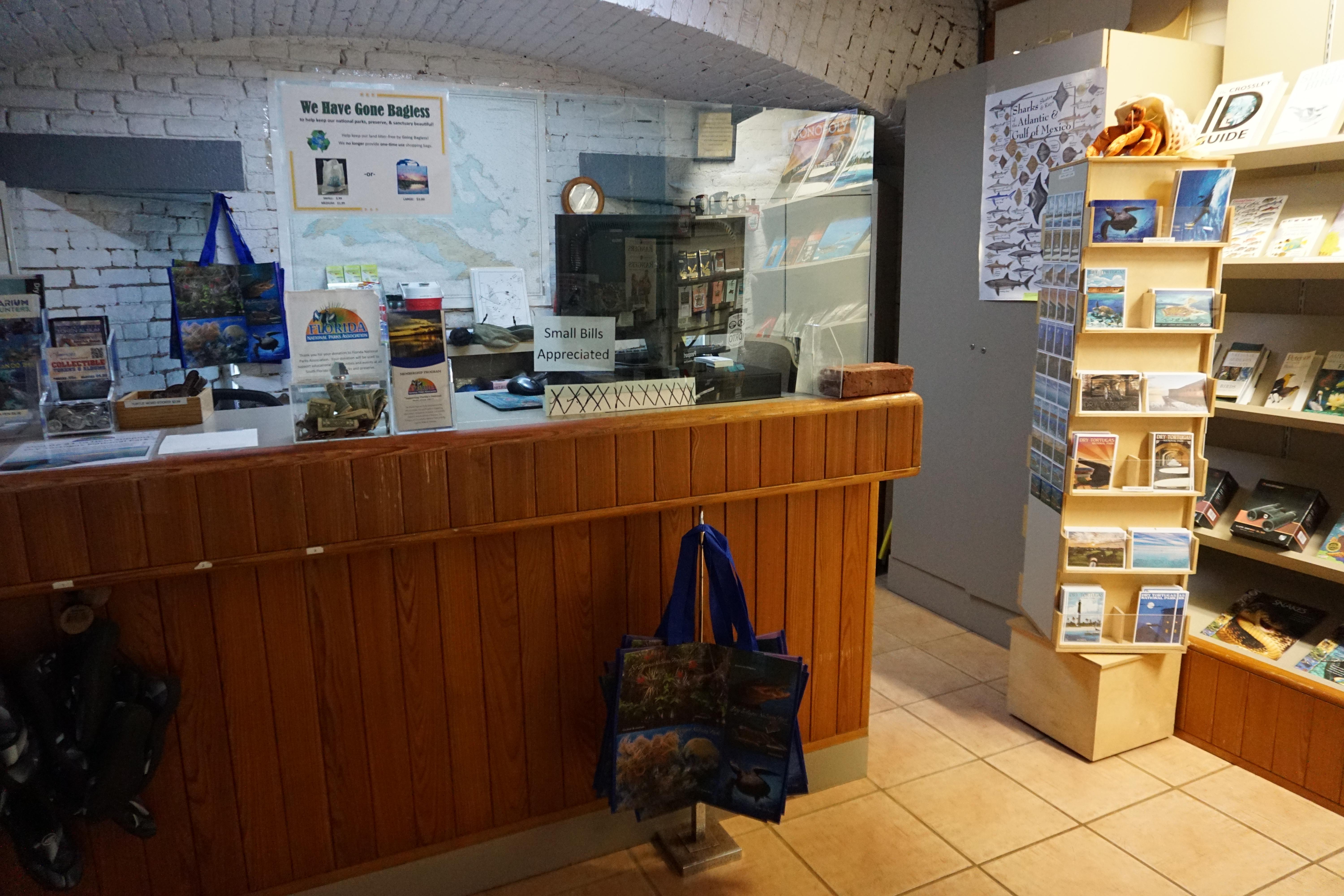 A wooden desk contains colorful items such as postcards, bags and magnets available for purchase