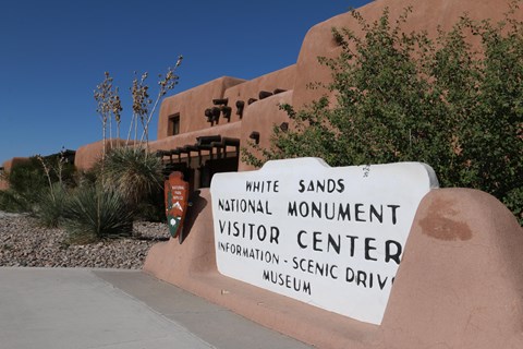 The White Sands visitor center sign in front of the adobe visitor center building.
