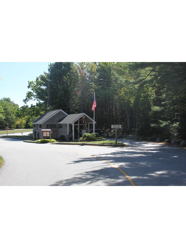 A wooden building with a flag pole and signs