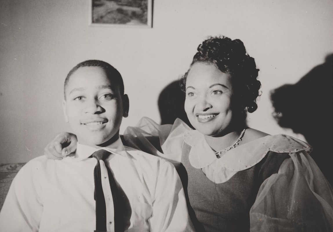 Two African Americans sitting in a room and smiling toward the camera. 