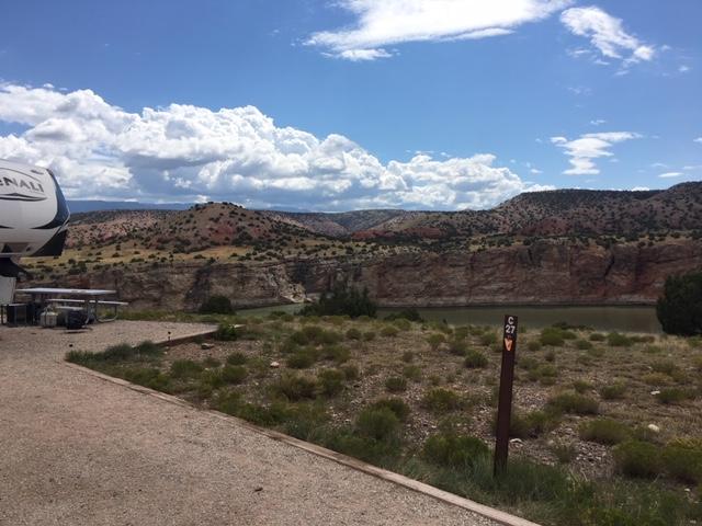 A gravel drive through campground with the canyon and lake in the background.