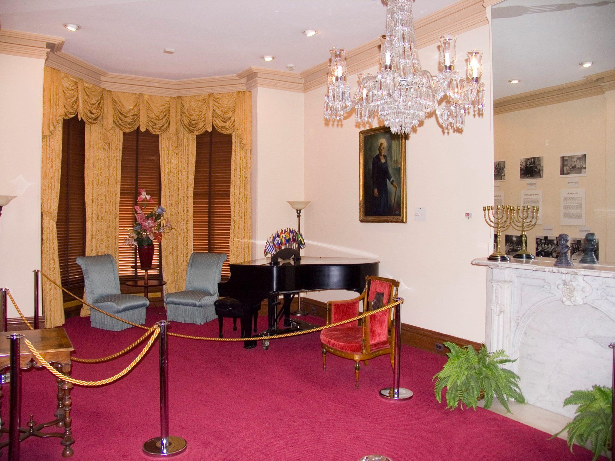 A room with ornate furniture, crystal chandelier, large mirror, and large portrait of Mrs. Bethune