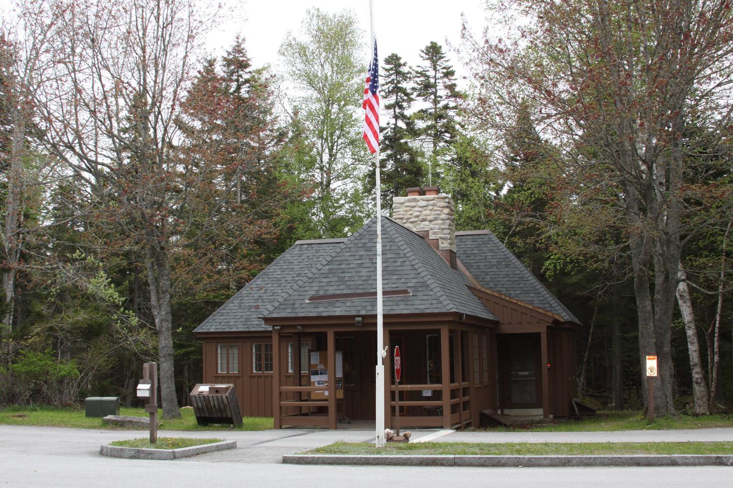 A wooden building with a flag pole and signs