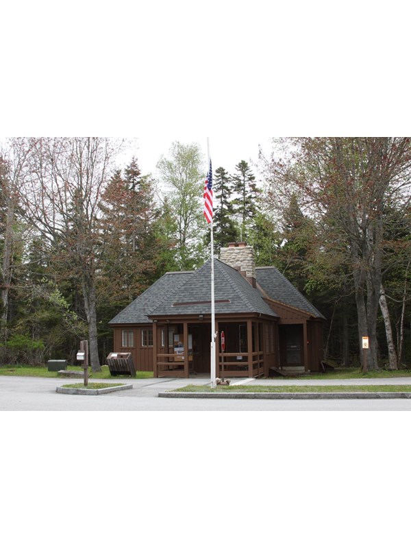 A wooden building with a flag pole and signs