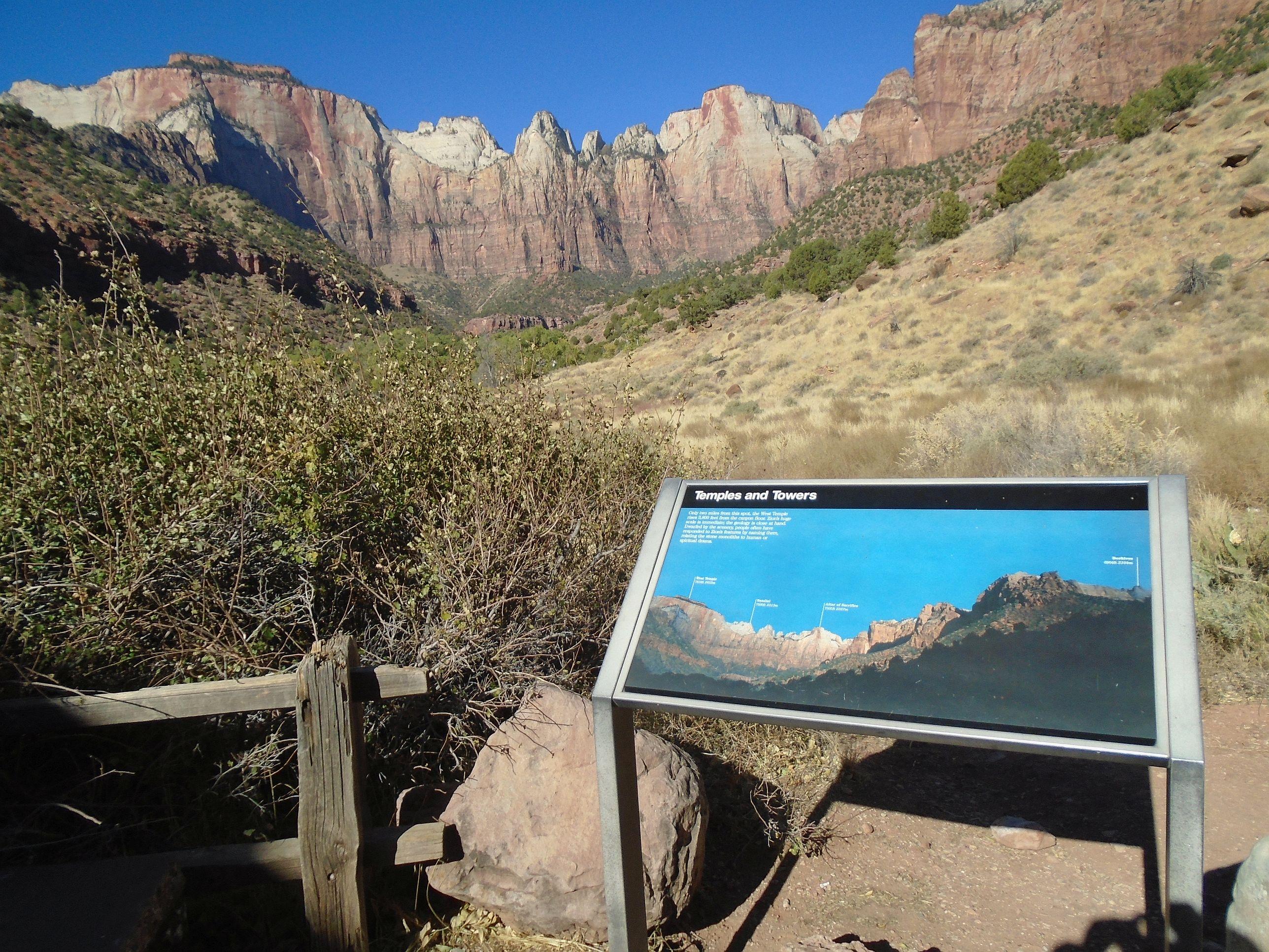 A sign describing the view of a large rock formation in the background