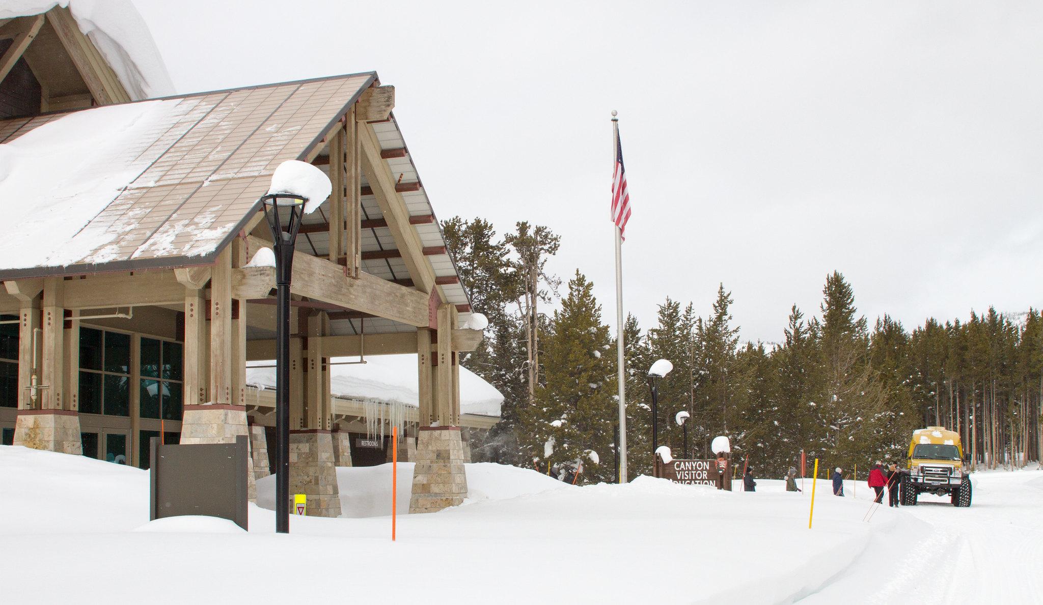 A snowcoach parked in front of a snow-covered visitor center.