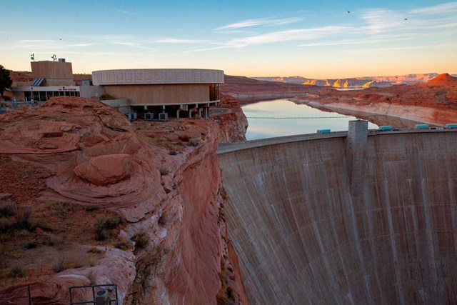Modern visitor center building on the edge of a cliff above Glen Canyon Dam at sunrise