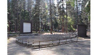 Empty amphitheater in campground with benches and a screen and stage