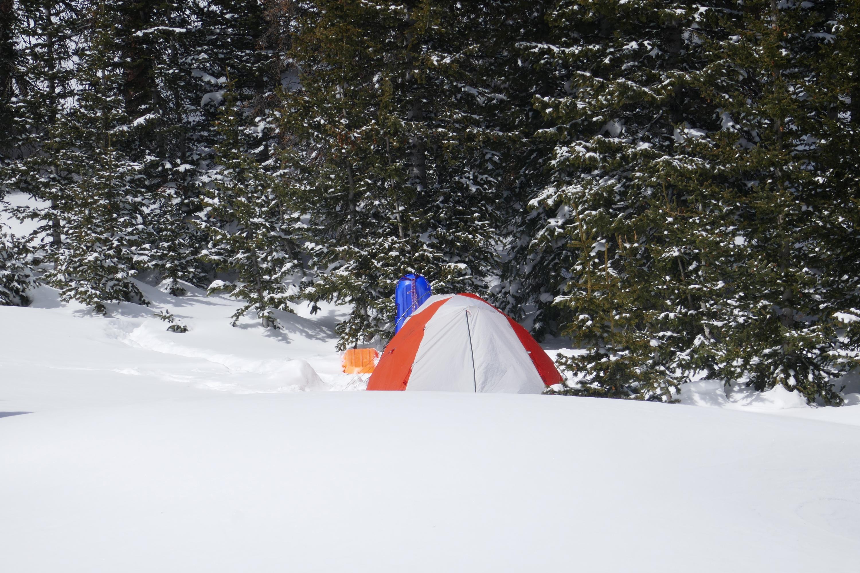 A tent is surrounded by snow on the ground