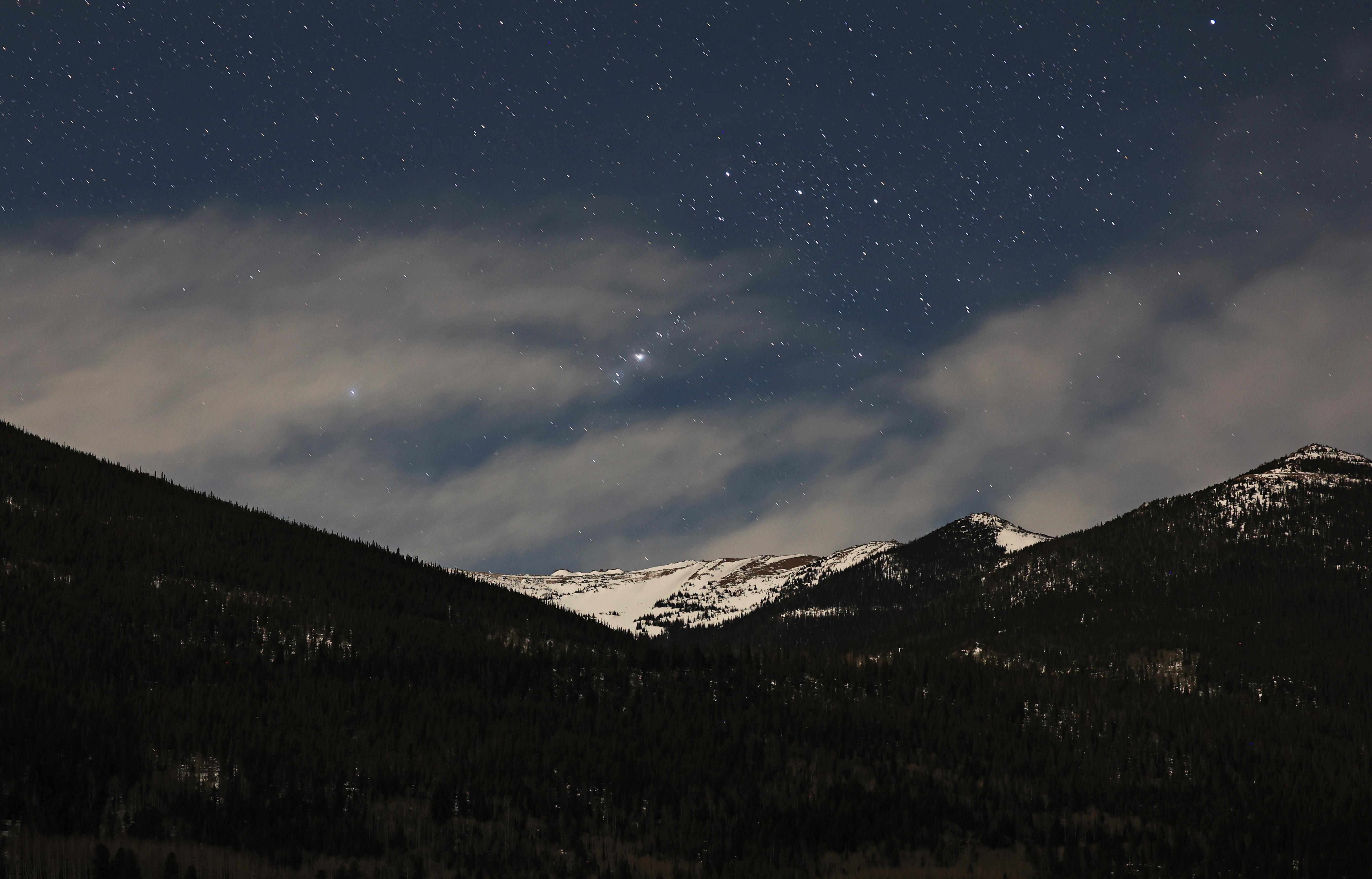 Stars are in the sky, over mountain peaks, at night