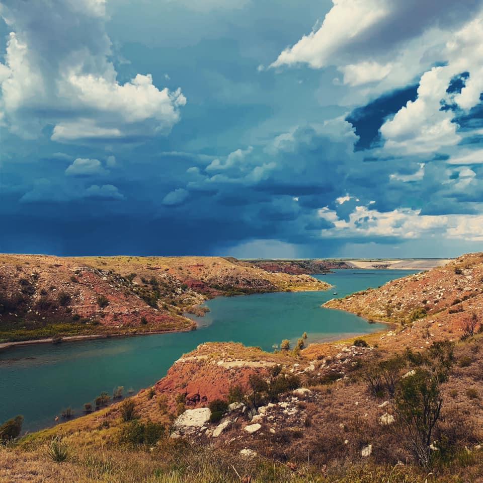 A storm coming in at Lover's Canyon.  The sky is dark blue with dark clouds.  The lake is greenish.