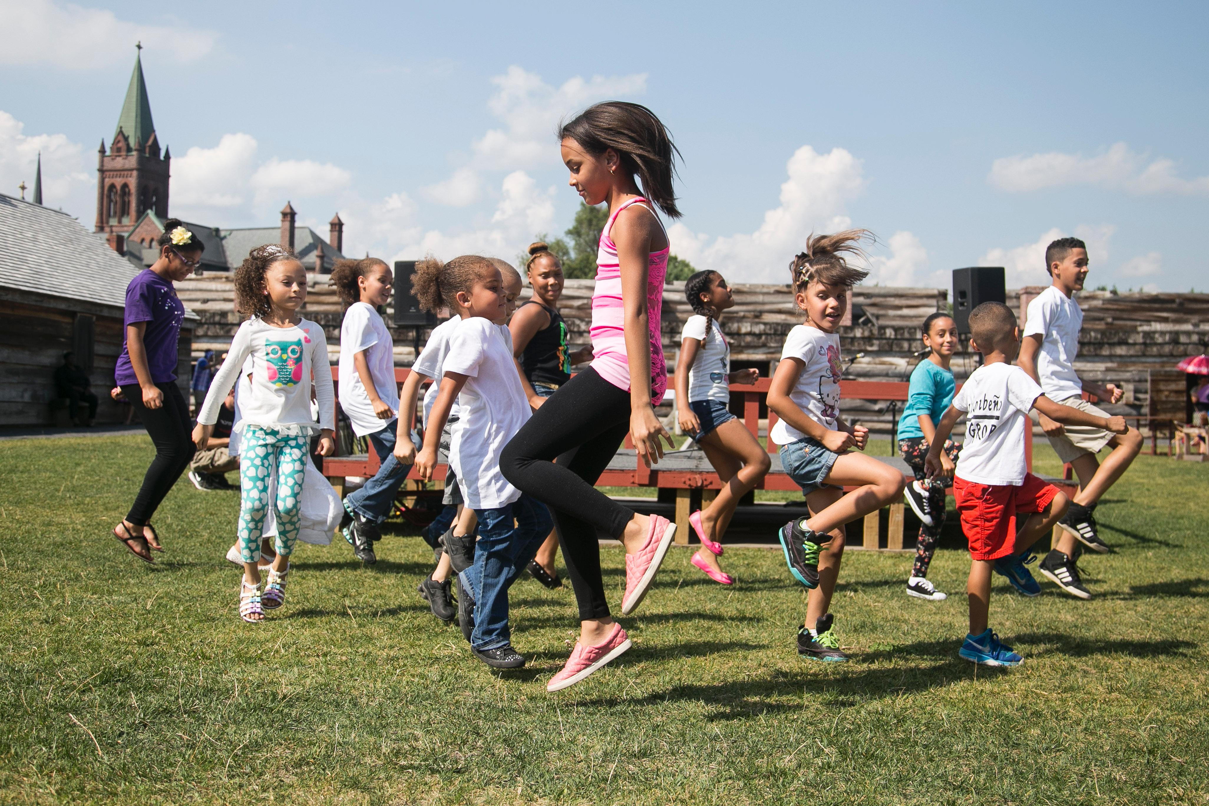 Children dance, jump, and skip on the parade ground of reconstructed Fort Stanwix.