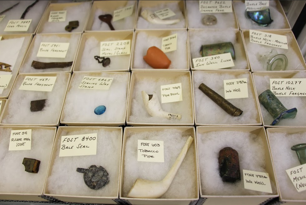 Small boxes in rows contain small artifacts, including broken pipes and glass bottles.