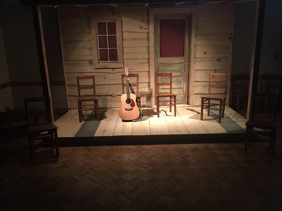 guitar sits on a dimly lit porch styled stage