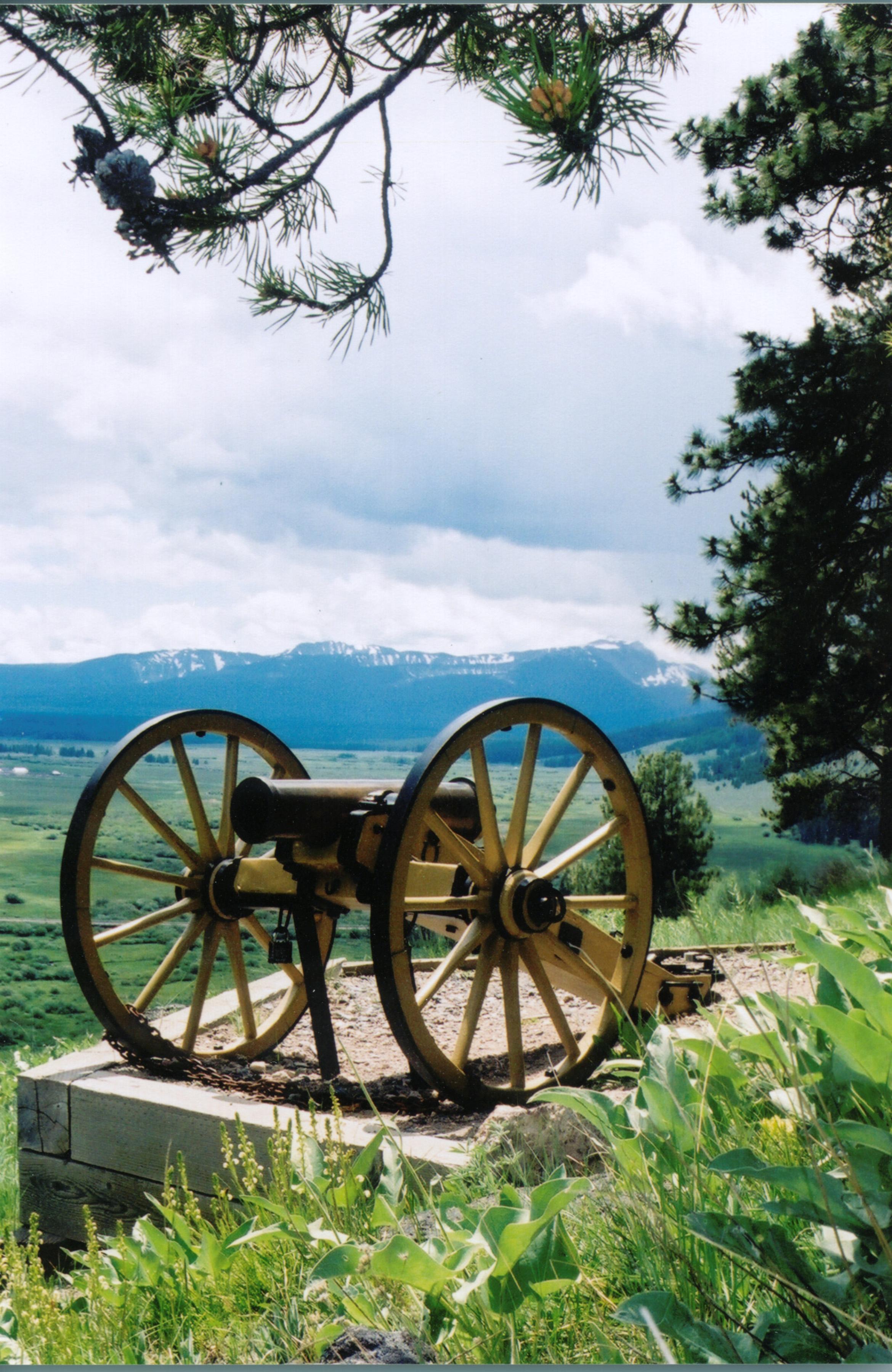 a cannon overlooks a valley and distant mountains
