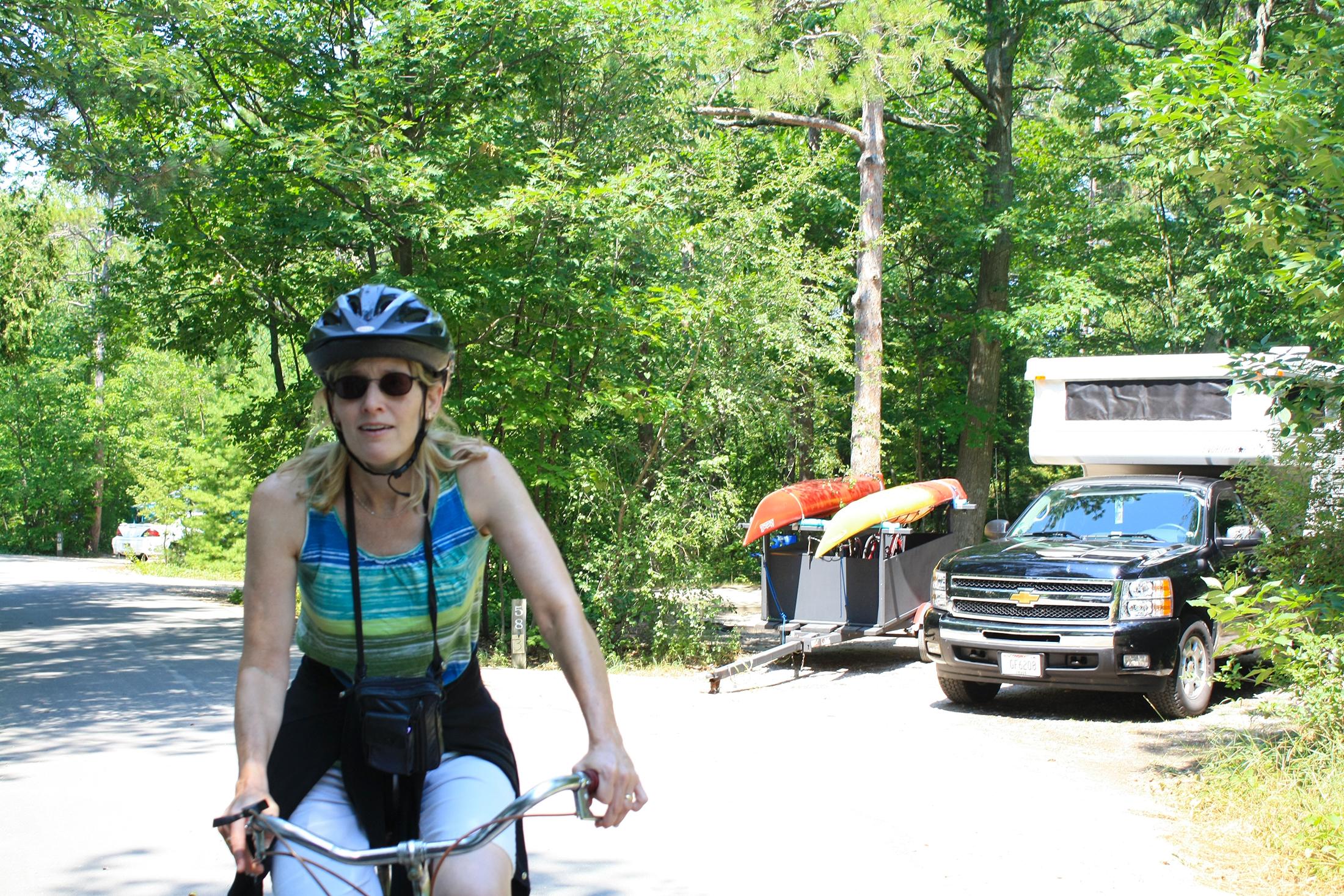 Woman on bike riding by a campsite.