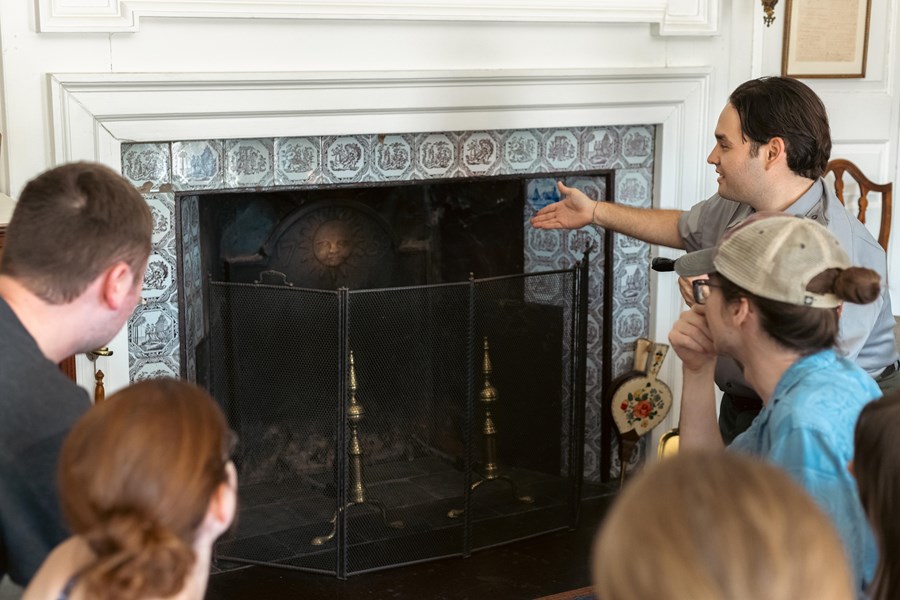 Park ranger and visitors crouch in front of an 18th century fireplace