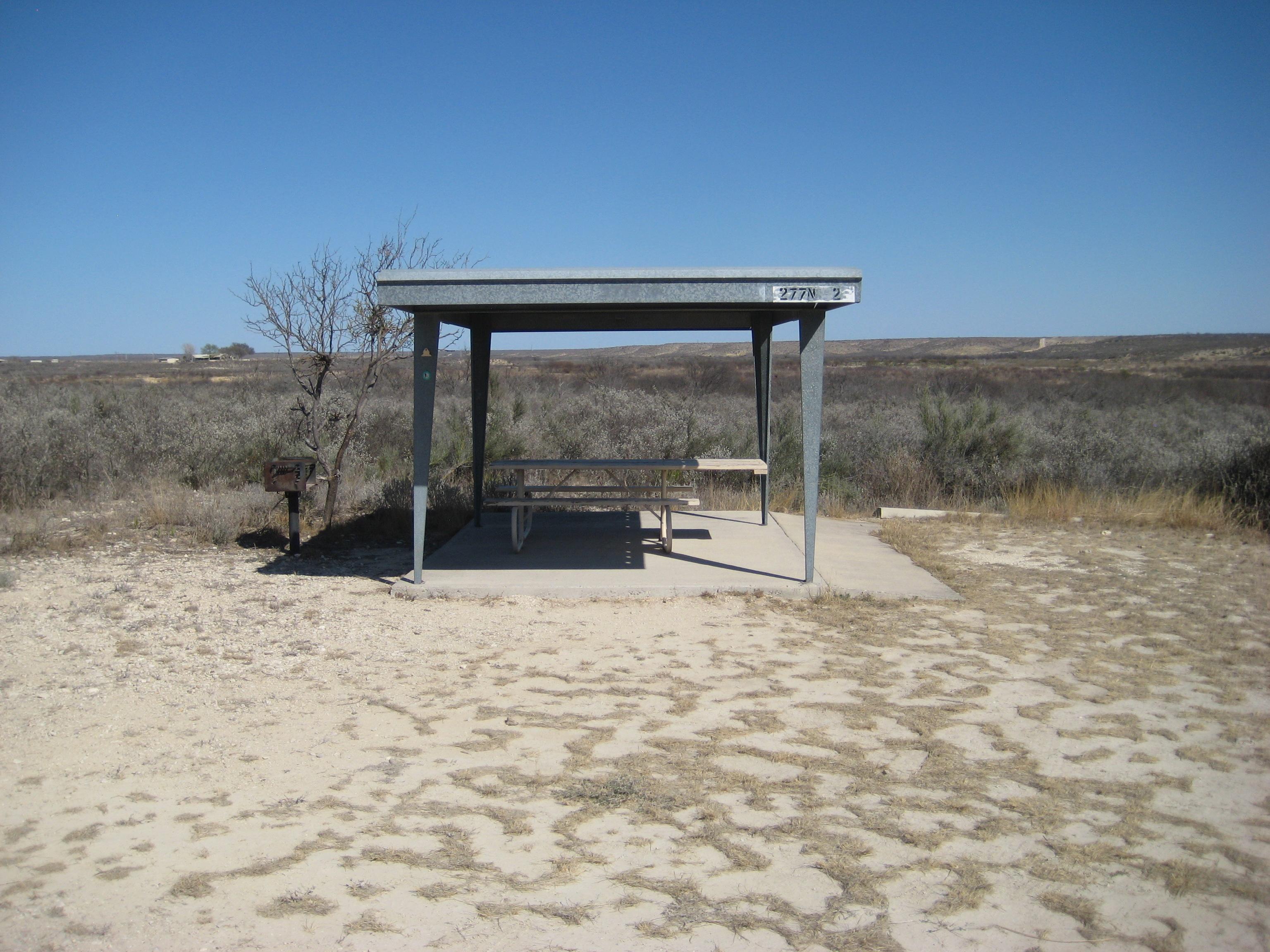 Picnic table on cement pad under metal shade shelter