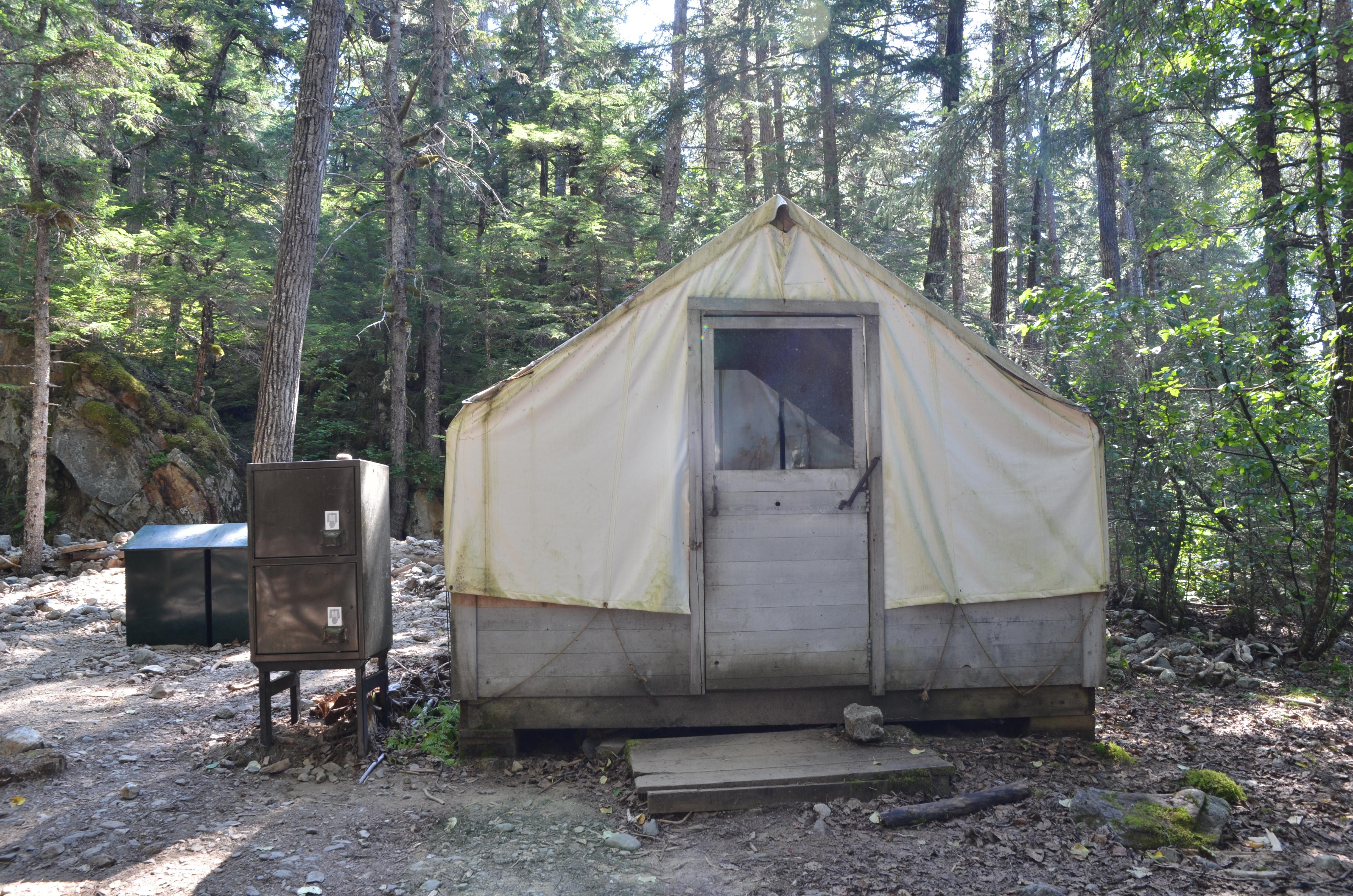 White canvas wall tent and two metal bear storage containers