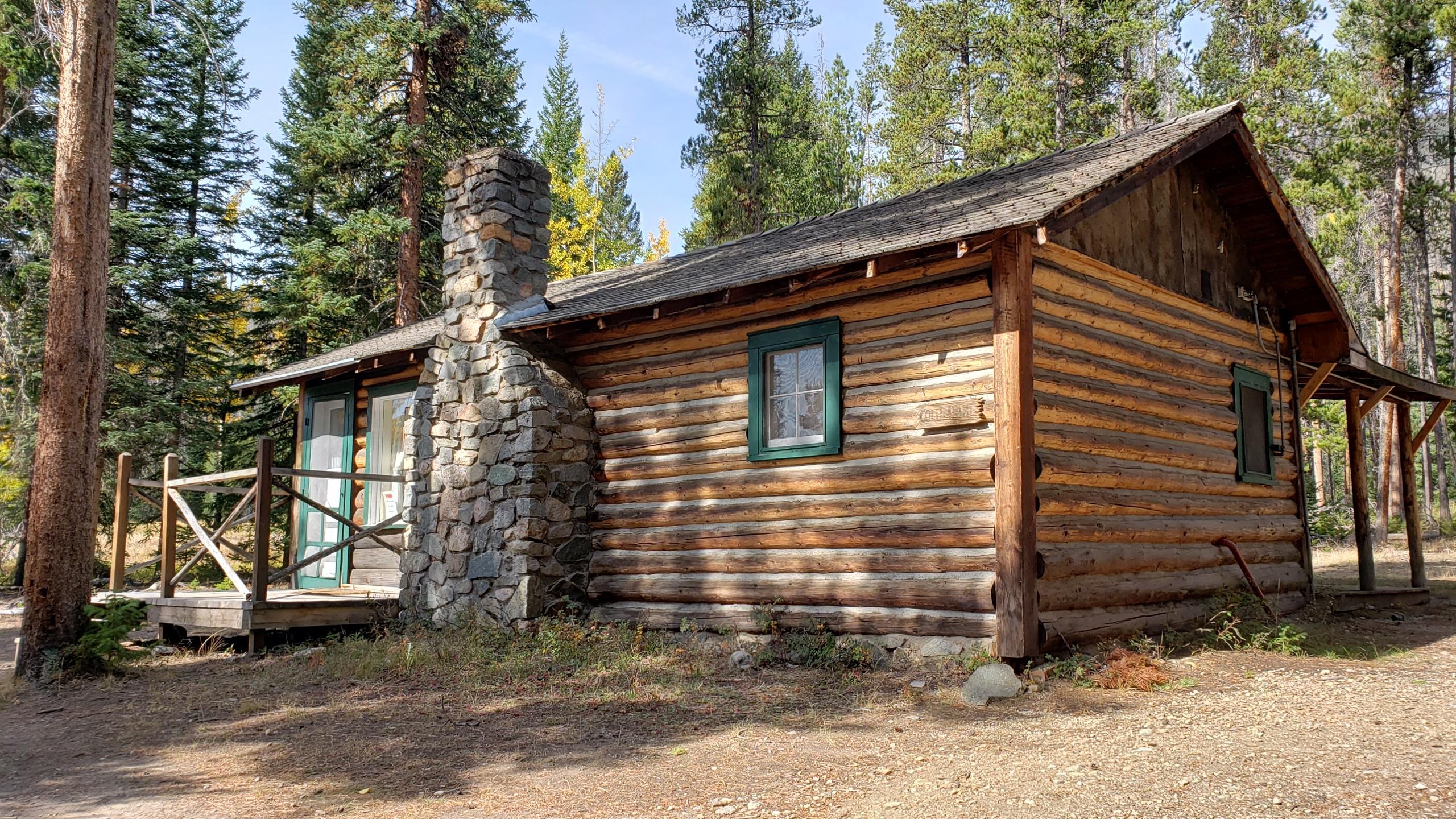 View of a wooden cabin with a stone chimney
