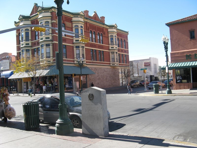 El Paso Station Marker A large stone monument sits on the side of a historic city street with brick buildings.