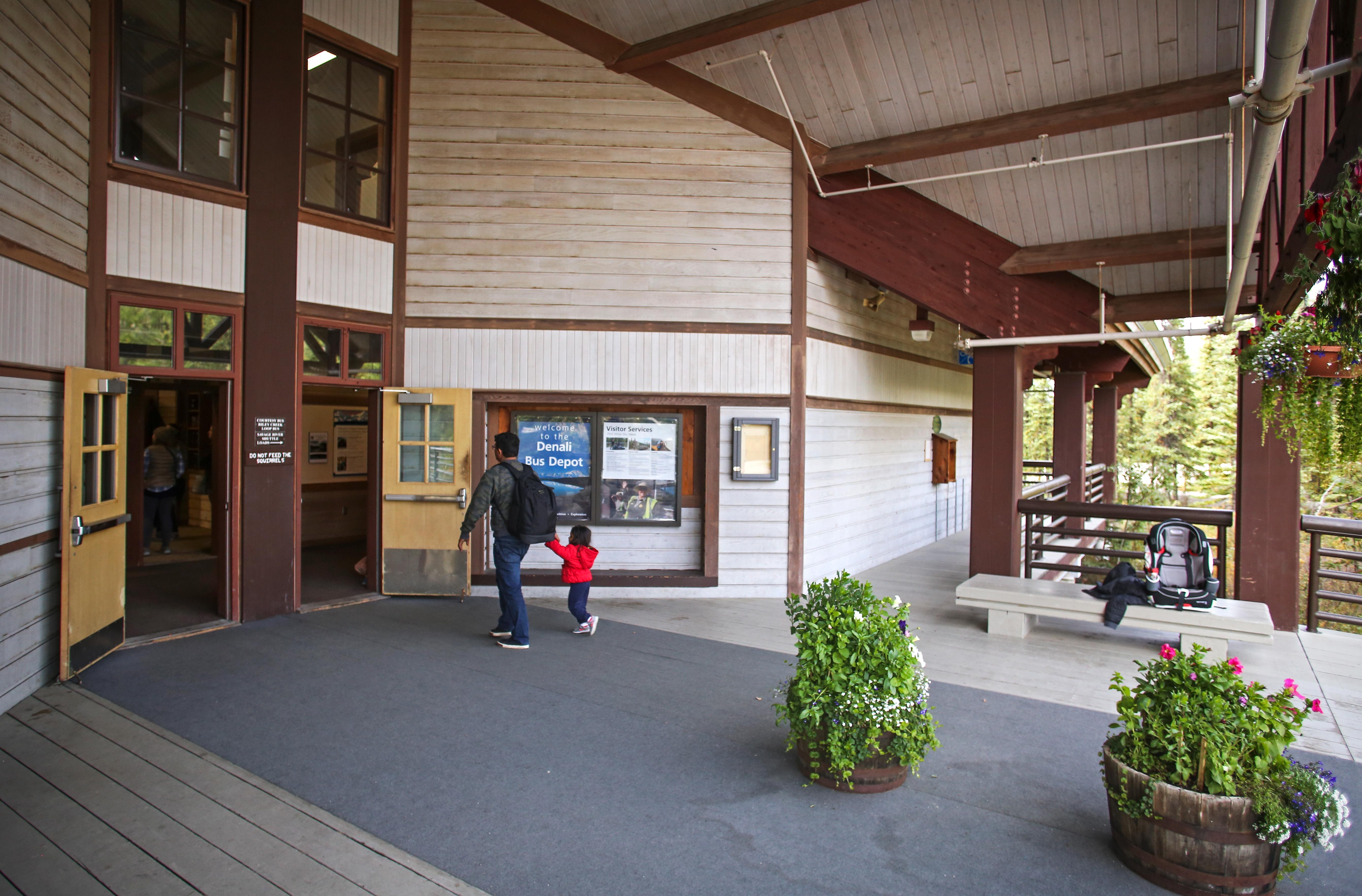A man and child walk through the front doors of the Denali Bus Depot.