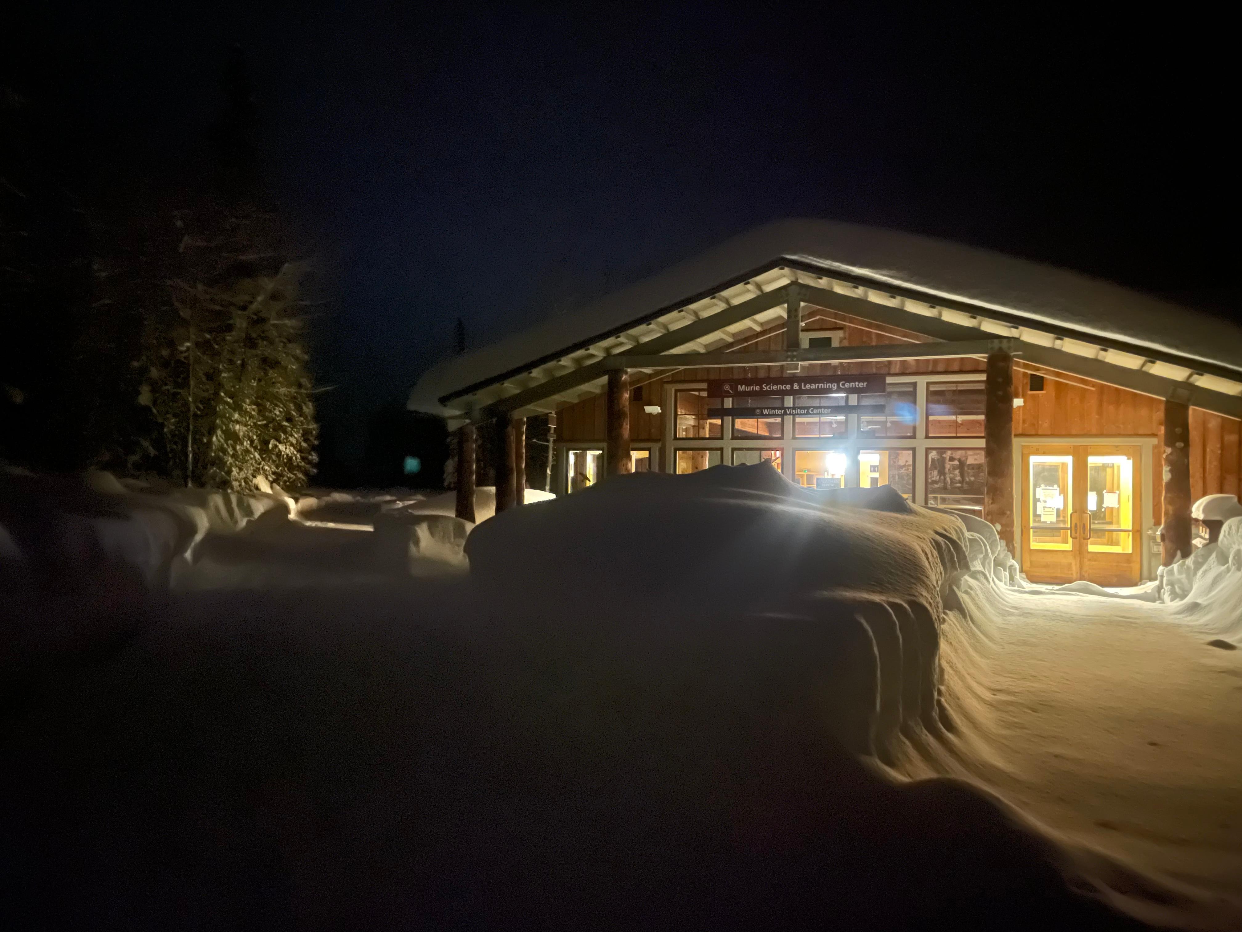 The MSLC glows from within at night, and a snowy path leads to the front door.