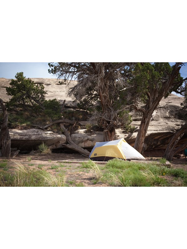 a yellow tent nestled against a rock outcropping