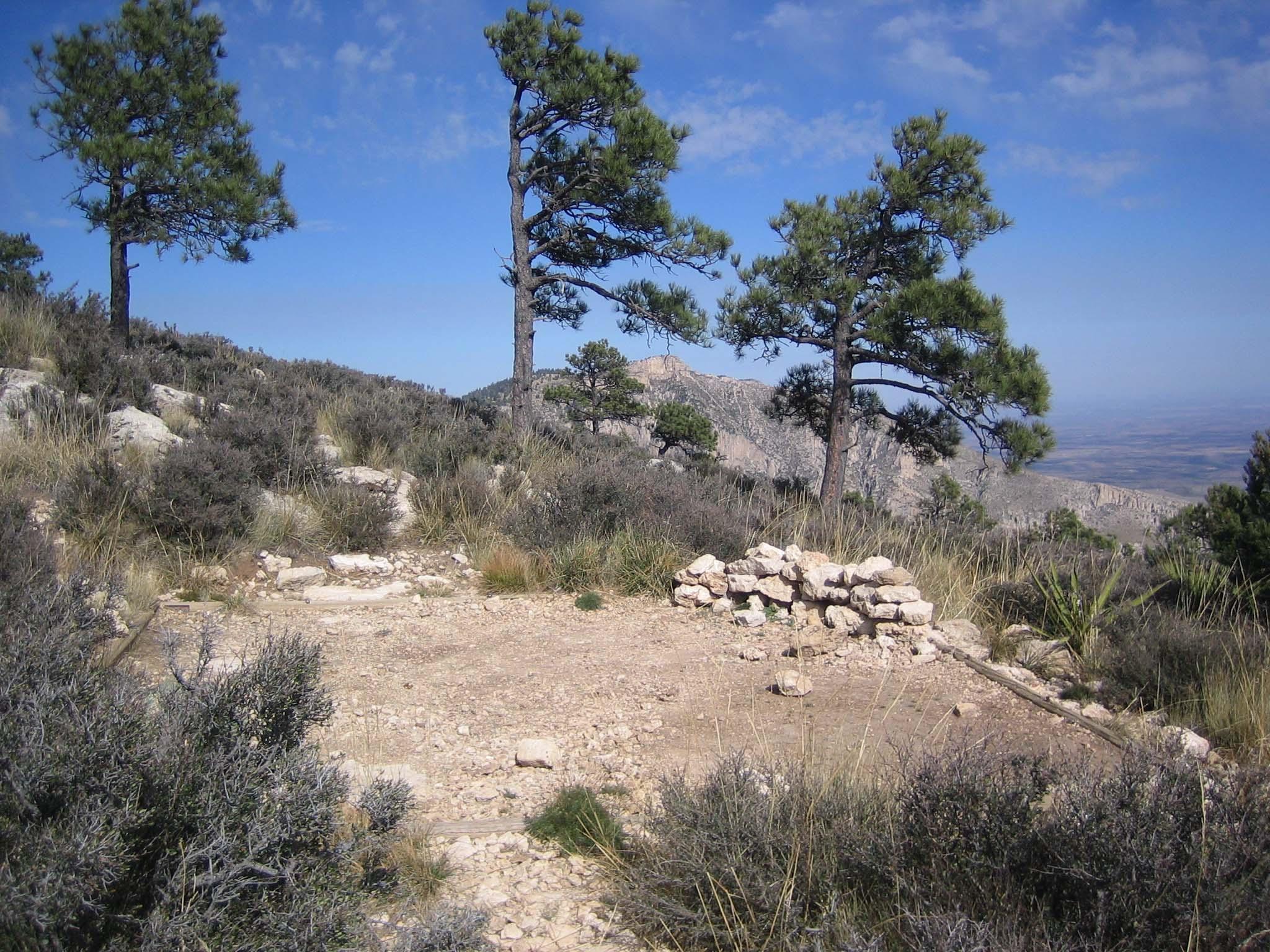 A hardened pad for a tent in a sparse mountain landscape with few trees