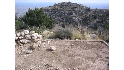 A hardened surface for a tent overlooks a steep rocky mountain landscape