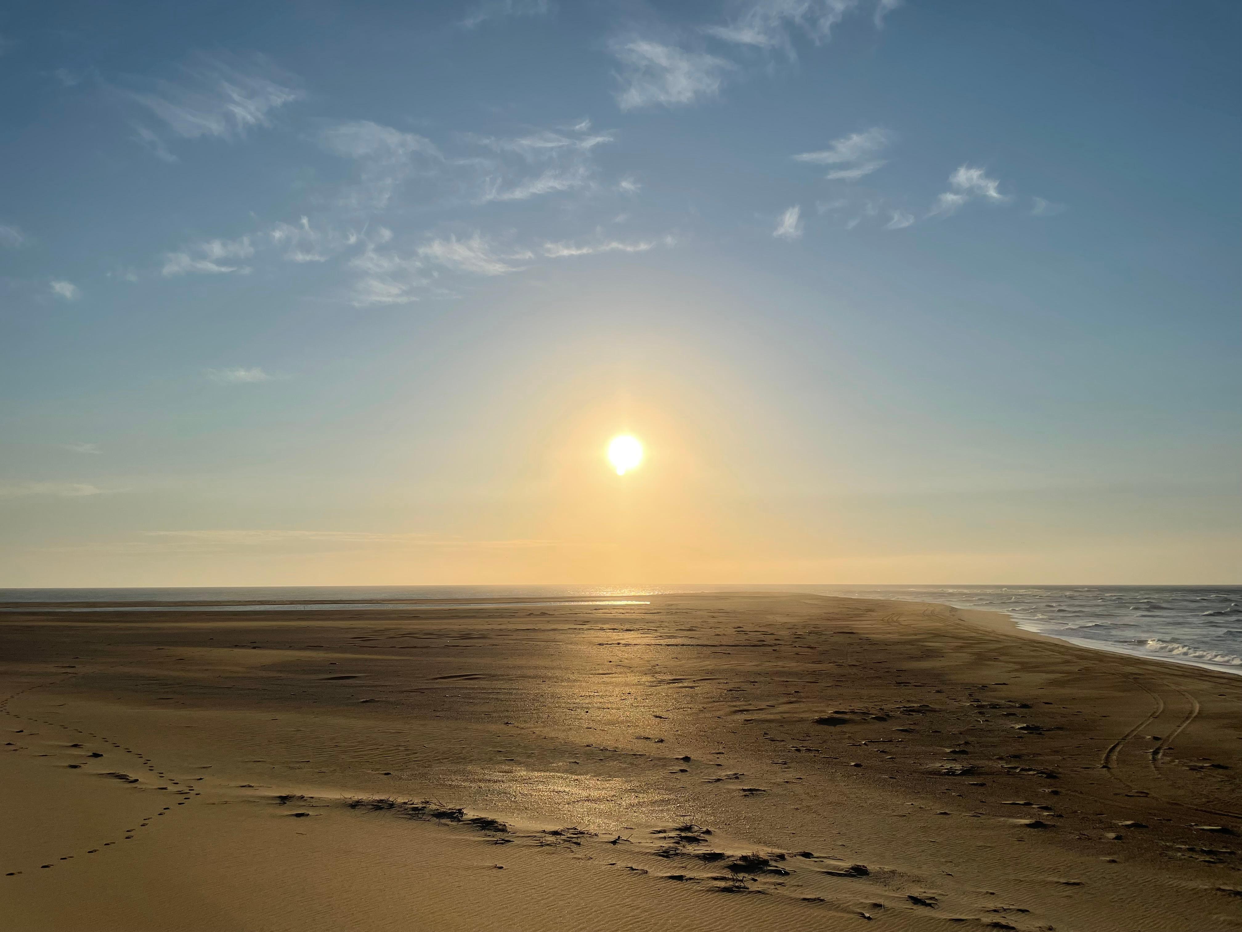 a yellow glow of the risiing sun over the beach and ocean
