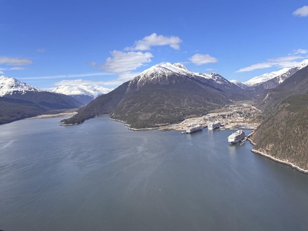 Aerial image of two inlets in a deep fjord, with a small city and large cruise ships tucked in one