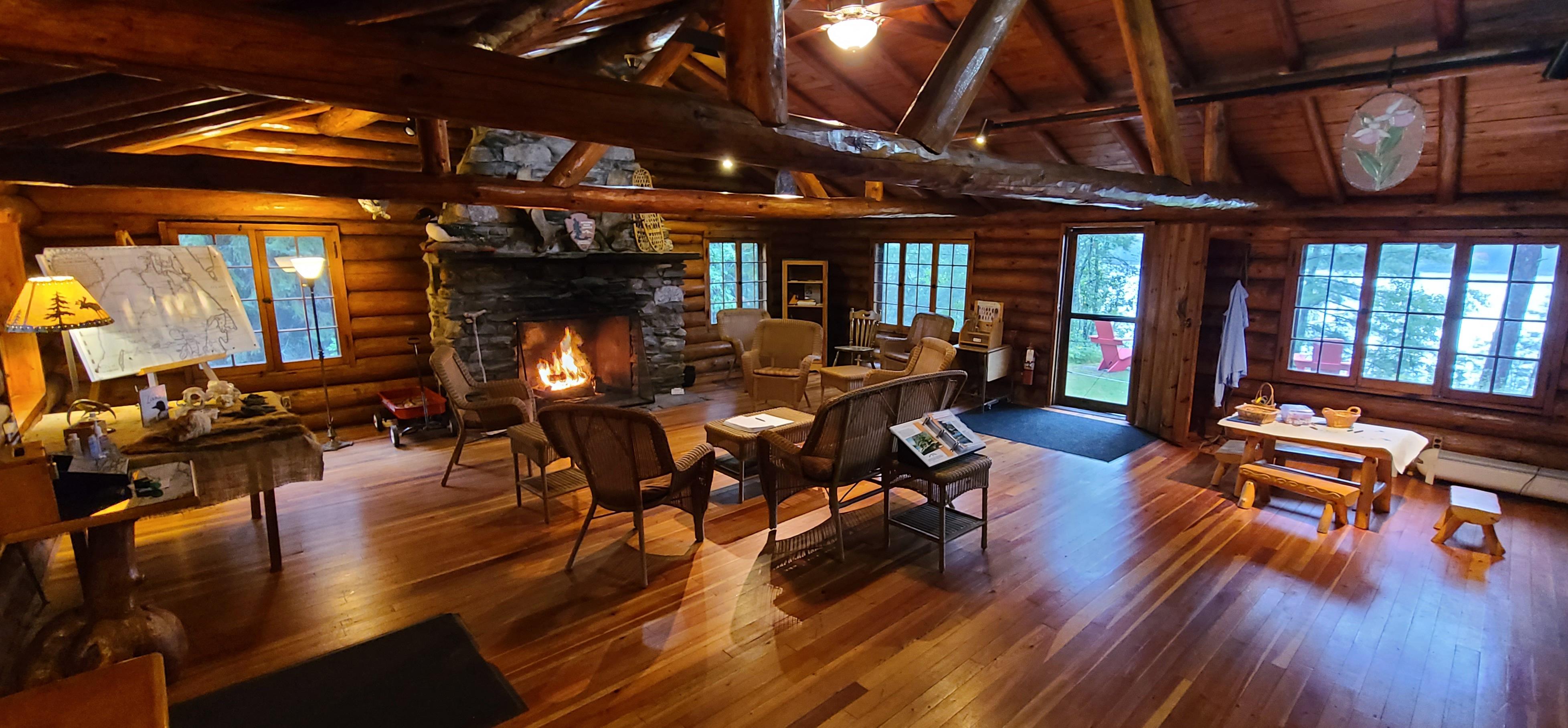 Photograph of interior of timber building with rustic furniture and a fireplace.