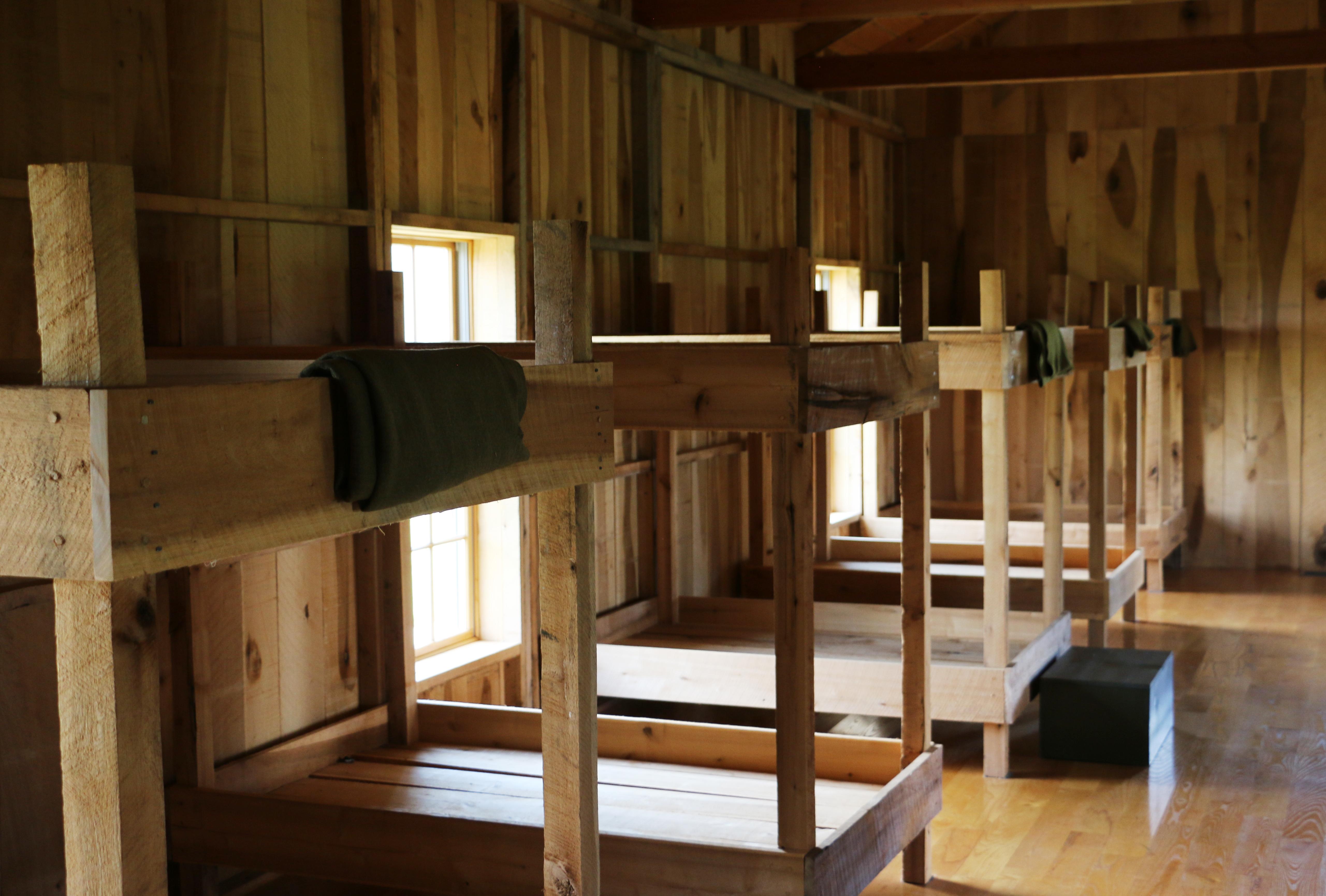 A row of rough, wooden bunk beds in the soldiers' barrack house.