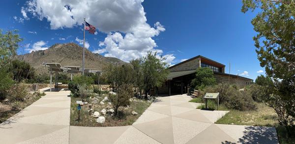 Paved walks lead to an outdoor plaza and a large building in a desert landscape