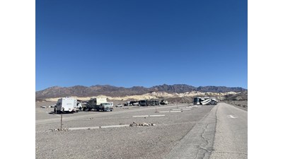 a roadway through gravel with RVs parked at spots marked by cement curbs