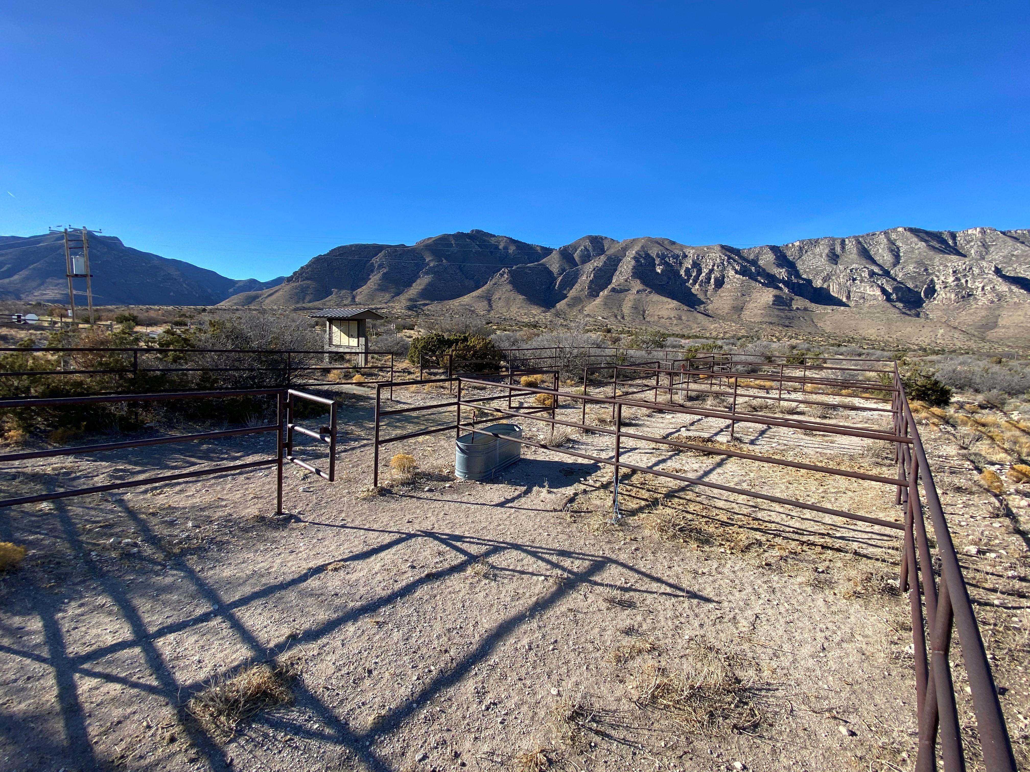 A fenced horse corral compound with desert mountains in the background