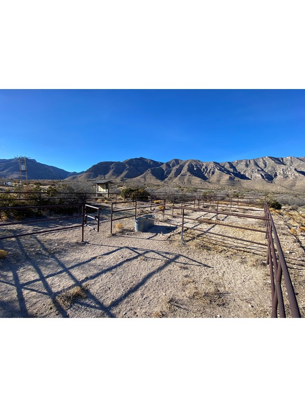 A fenced horse corral compound with desert mountains in the background