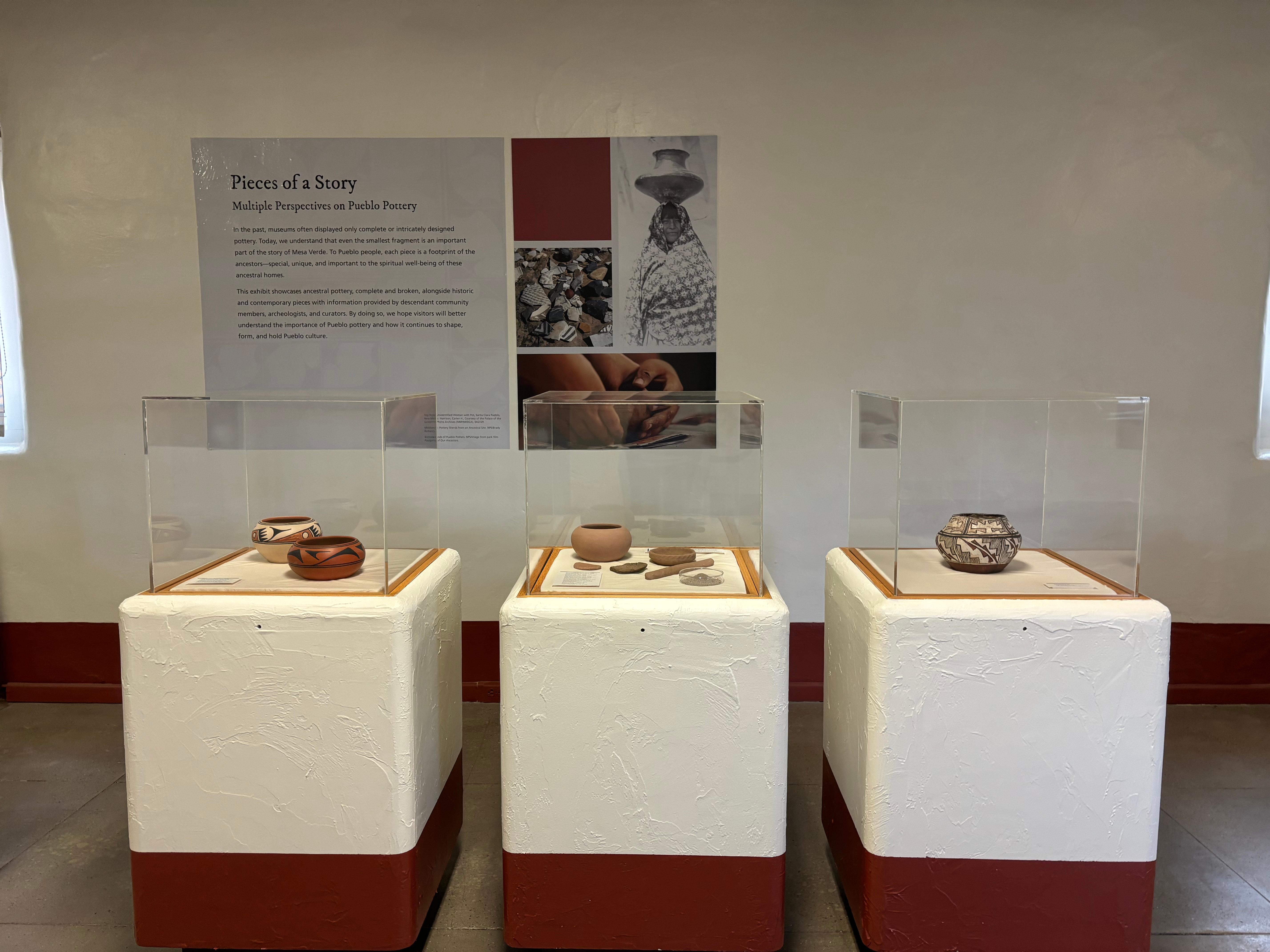 Three square exhibit cases with glass on the upper half showcase ancestral and contemporary pottery.