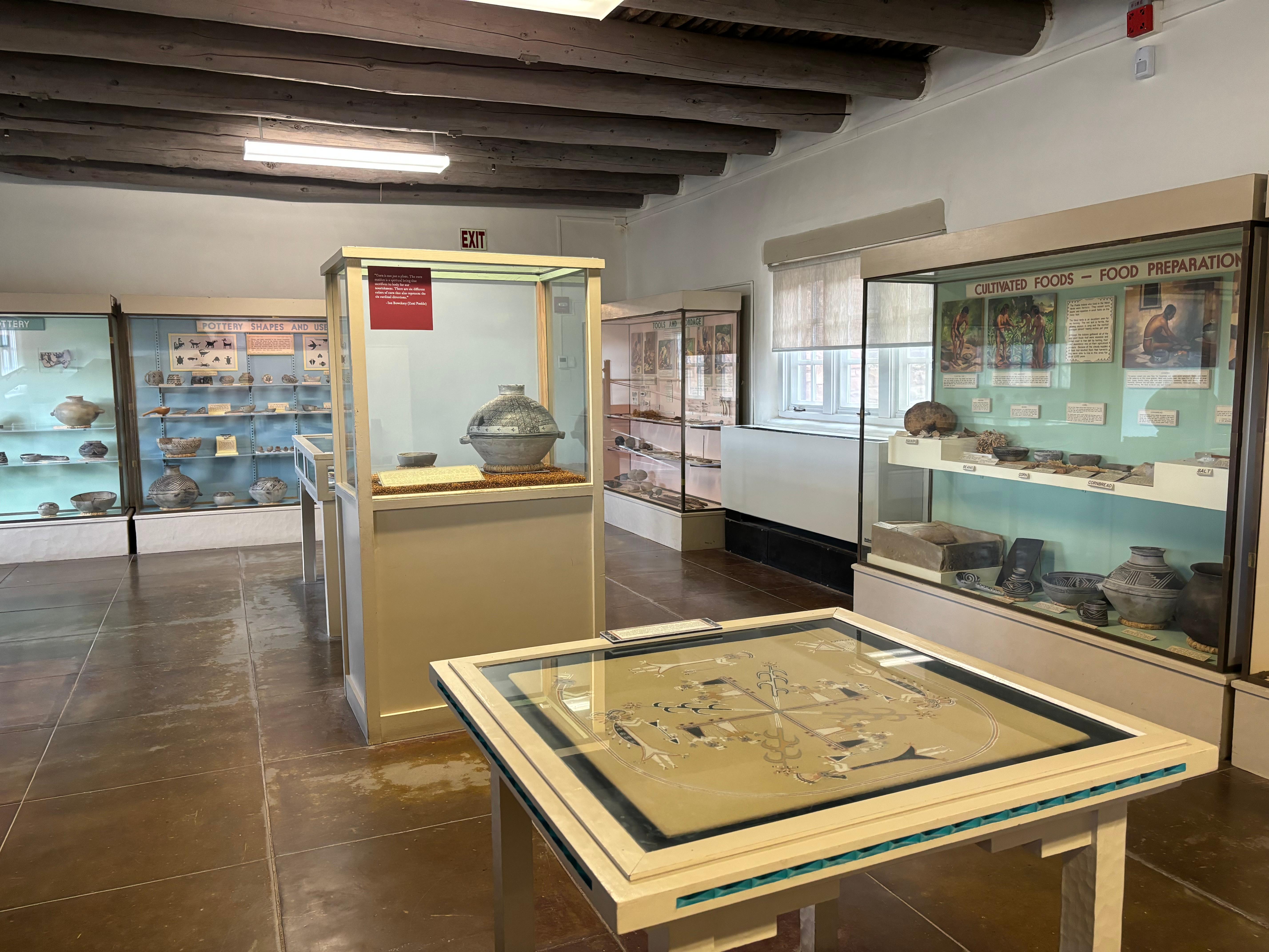 Seven glass displays showcasing Ancient Pueblo pottery, jewelry, and tools for cultivating food.