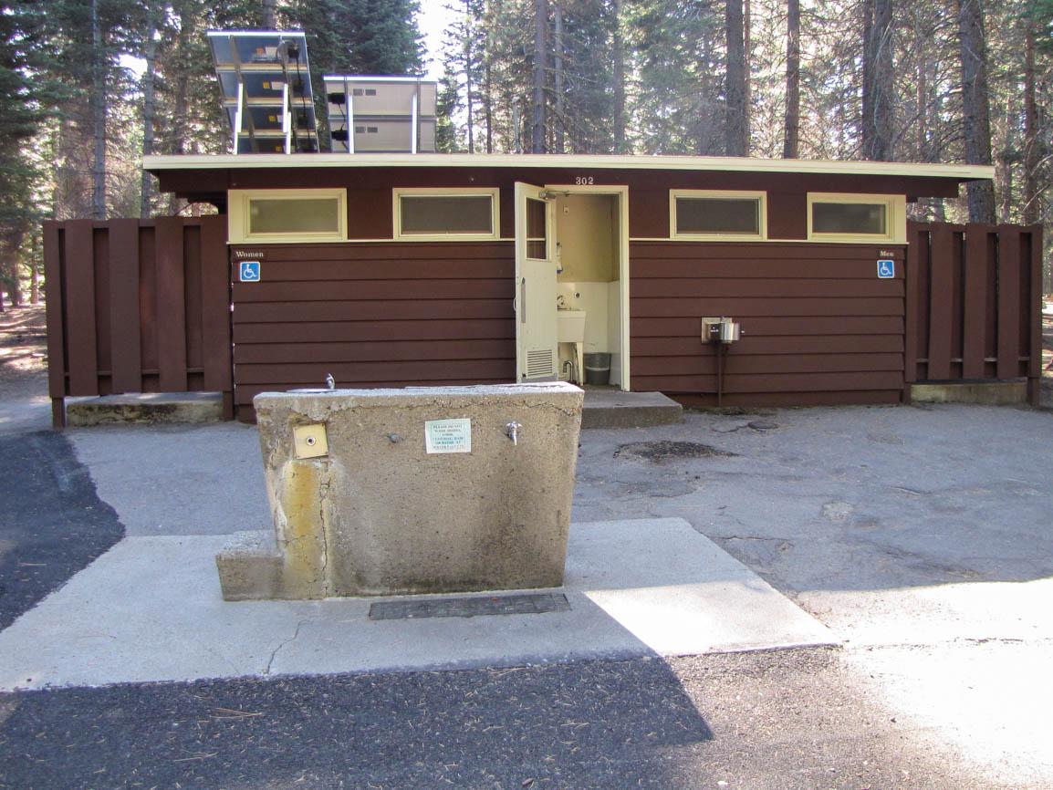 A brown building with restrooms, a utility sink, and a water spigot out front.