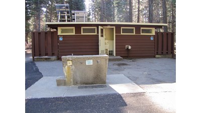 A brown building with restrooms, a utility sink, and a water spigot out front.