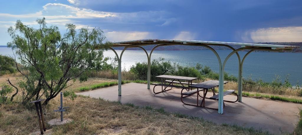 Picnic shelter at a campsite overlooking Lake Meredith.  The sky is blue with no clouds.