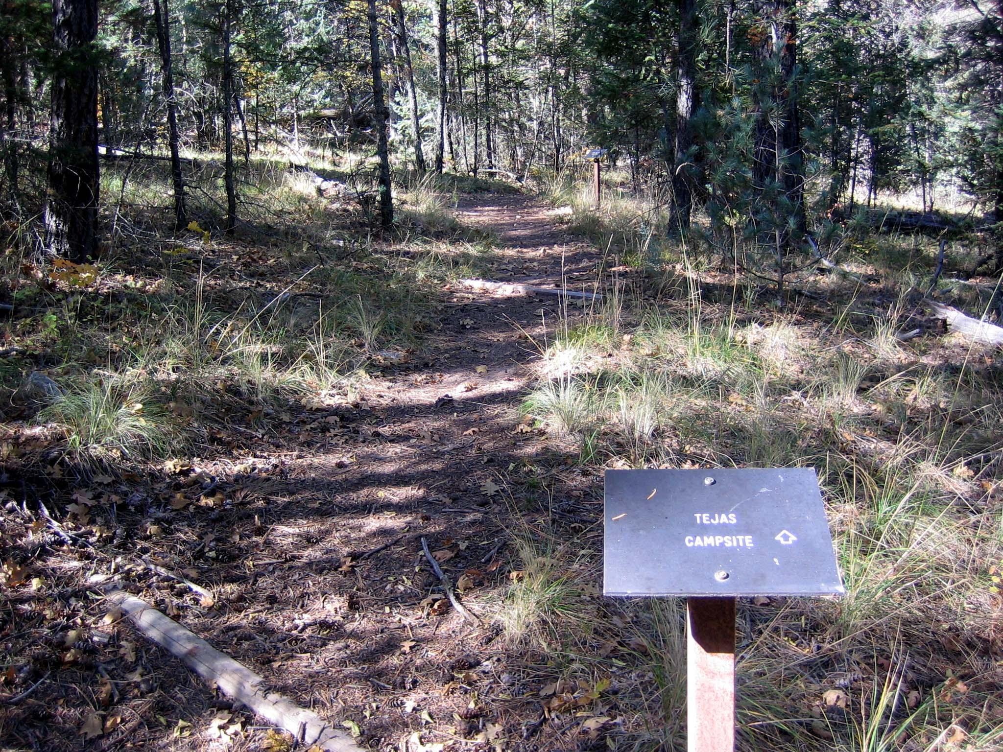 A metal sign directs hikers to the Tejas campground